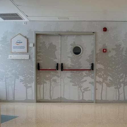 Imagen de la puerta y la pared con el diseño de vinilo que forma parte del proyecto de diseño de interiores para la Fundación Aladina