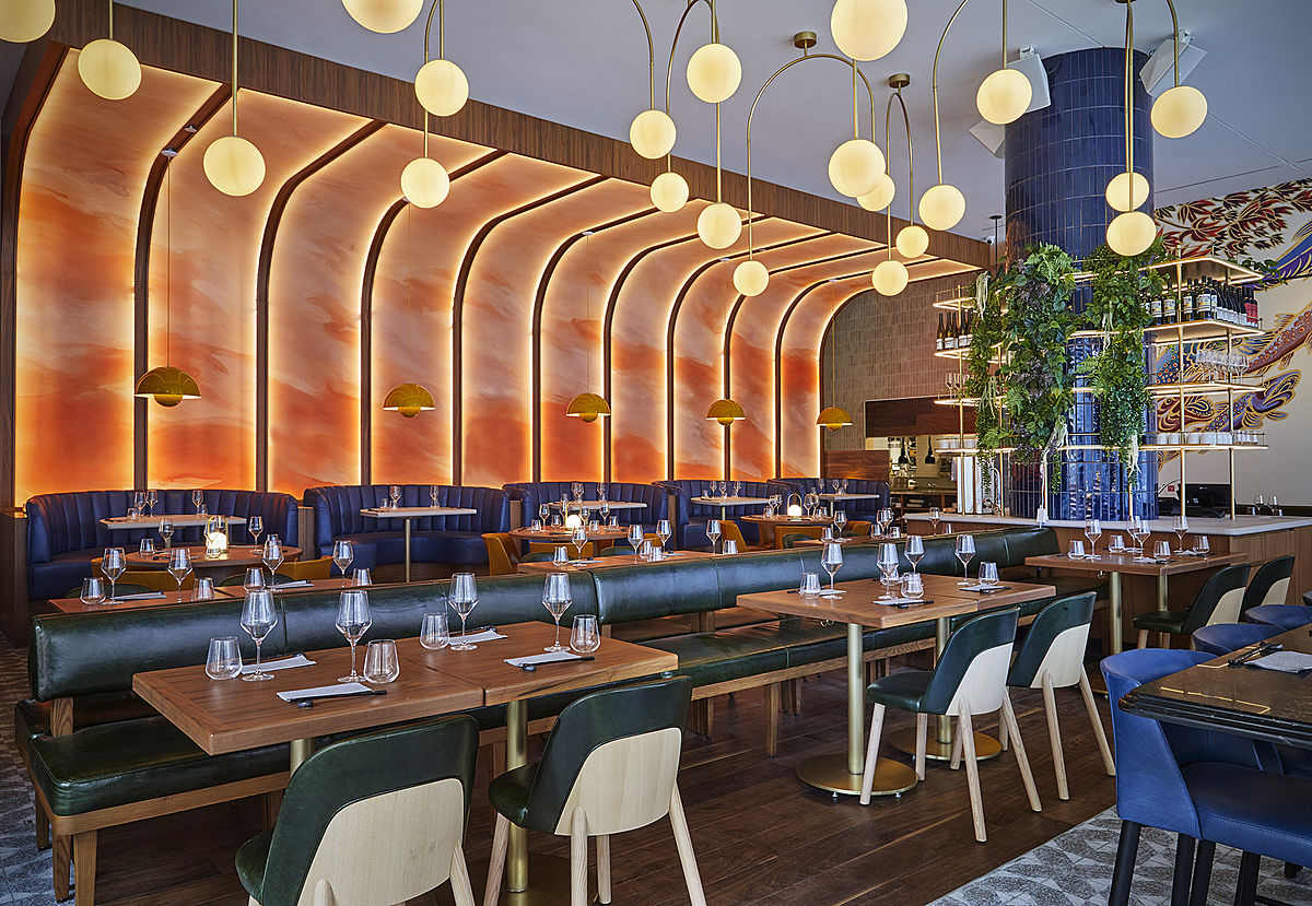 Imagen de las mesas y la pared curva en forma de pieza de salmón del diseño de restaurantes Minami